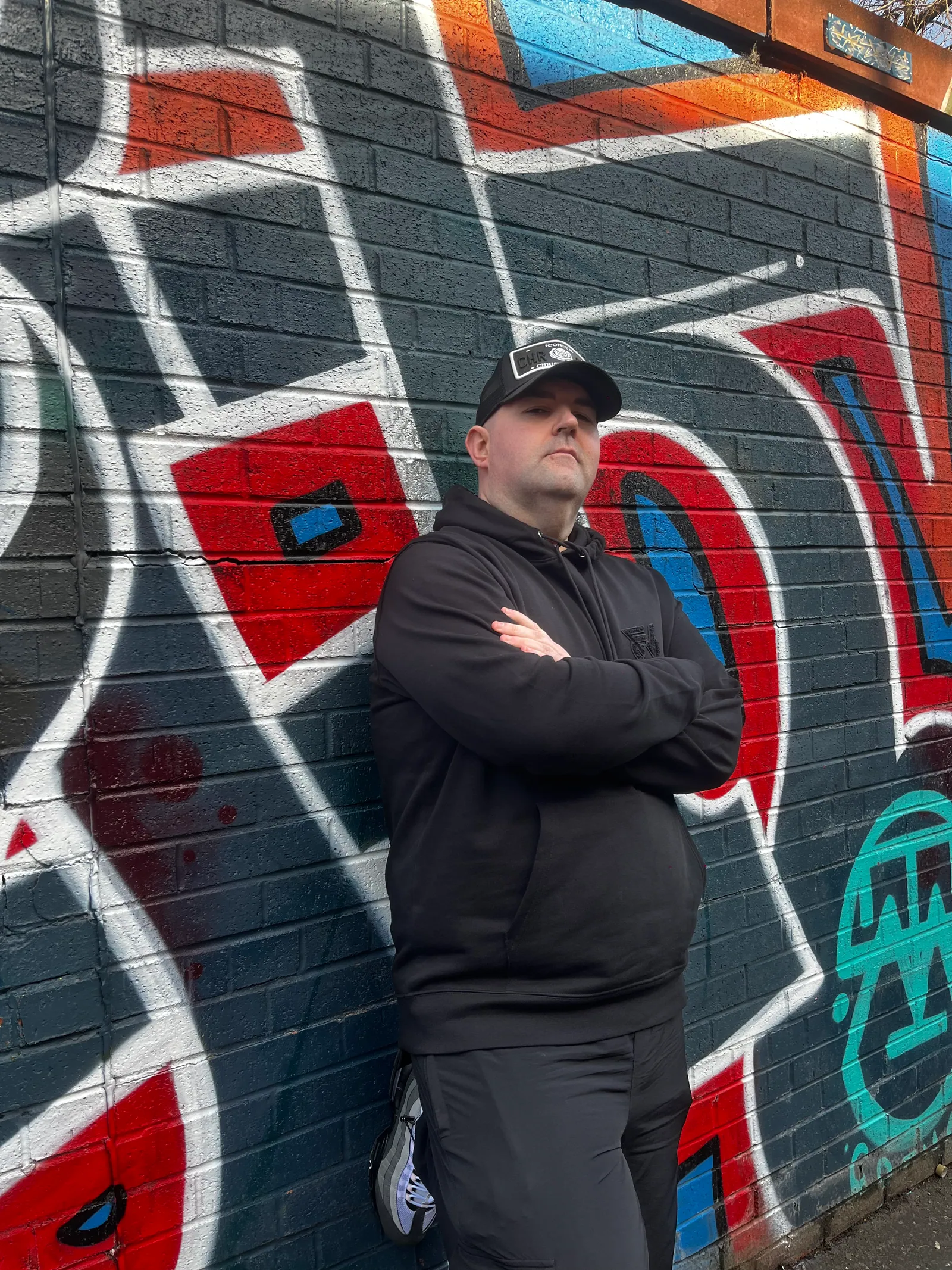 Macca standing by a graffiti wall